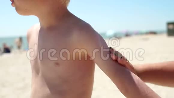 母亲在海滩上给孩子的皮肤涂防晒霜视频的预览图