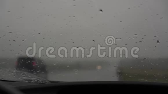 在挡风玻璃外的大雨中模糊的汽车在路上行驶视频的预览图