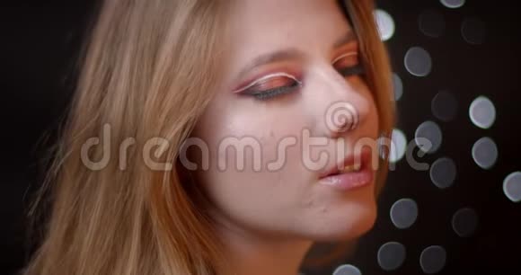 有吸引力的生姜模型的轮廓拍摄与明亮和生动的化妆调情相机在bokeh背景视频的预览图