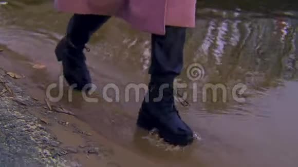 在沙质海岸和水边行走的女性皮革黑色靴子库存录像一个年轻人的细节视频的预览图