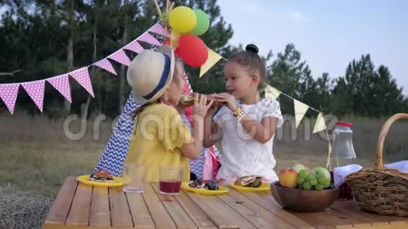 可爱的饥饿的孩子们在森林野餐时吃烘焙的糕点在孩子们在wigwam的聚会上喝果汁视频的预览图