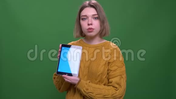 年轻迷人的短发女性的特写镜头使用平板电脑显示蓝色屏幕与背景相机视频的预览图