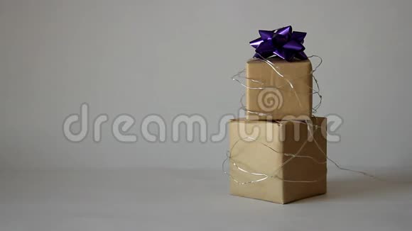 手工纸盒中的礼品包装在灯光背景下闪烁的灯光花环中视频的预览图