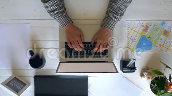 男性手在白色木桌上的笔记本电脑键盘上打字商人用笔记本做他的工作俯视图视频的预览图