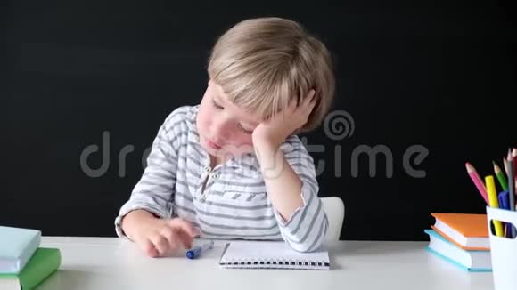 可爱的小男孩在学习时感到无聊小学的孩子在黑板上教育观念视频的预览图