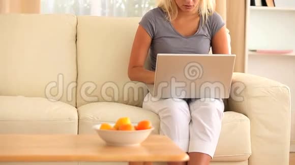 穿着衣服的女人坐在沙发上拿着笔记本视频的预览图