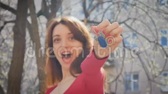 情绪化的年轻女人拿着蓝色钥匙链带着幸福和兴奋带红色指甲的女性手视频的预览图