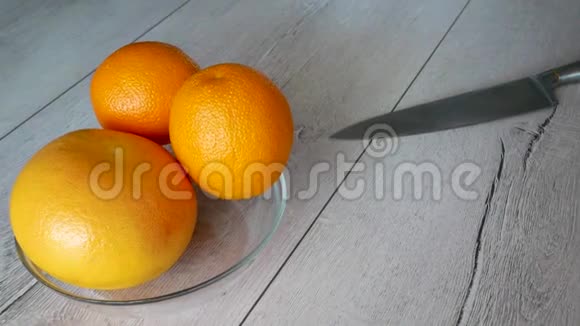 厨房里的女孩用一把大菜刀把一个橘子切成两半视频的预览图