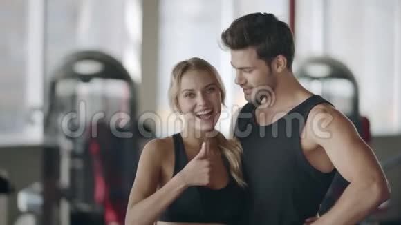 在现代健身房摆姿势的快乐夫妻微笑的女人竖起大拇指视频的预览图