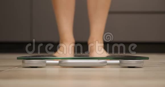 女人踩着秤女足检查厨房的体重测量体重的人腿近距离观看视频的预览图