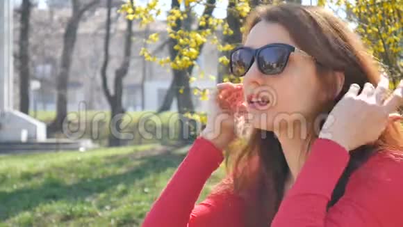 一个情绪激动的年轻女孩穿着红色衬衫摘下太阳镜看着镜头惊喜地花钱视频的预览图