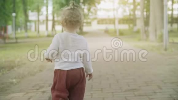 夏日里一个卷曲的金发女孩在公园散步慢镜头视频的预览图