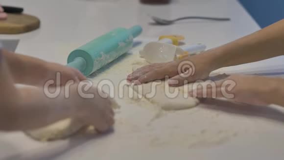 一家人穿着白色T恤用白色桌子上的面团做的特写的视频的预览图