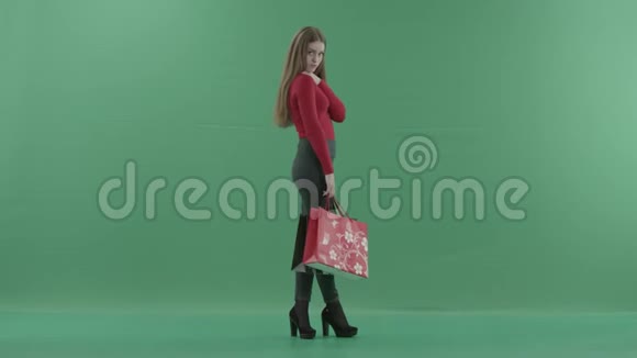 穿着休闲服的漂亮女人拿着购物袋在手机上说话她站在一边视频的预览图