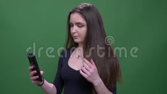 年轻漂亮的黑发女性在手机上拍摄可爱的自拍特写背景与绿色隔离视频的预览图