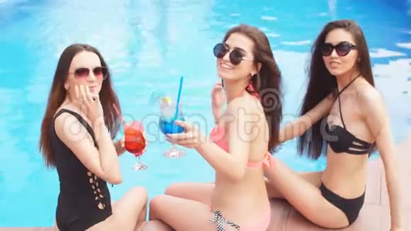 三个最好的朋友在泳池边放松聊天喝着清爽的鸡尾酒视频的预览图