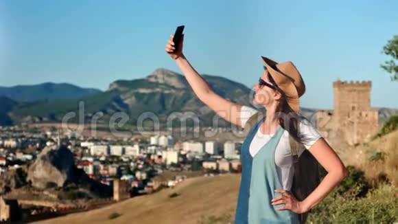 主动背包客年轻女游客使用智能手机站在山上自拍视频的预览图