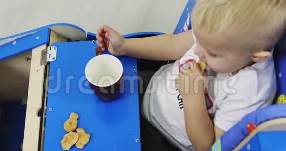 一个小男孩坐在他的公共汽车里吃饼干喝茶视频的预览图