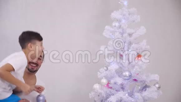 小儿子想把粉红色的宝布尔挂在树的顶枝上所以爸爸把他抱起来孩子做他想做的事然后做他想做的事视频的预览图