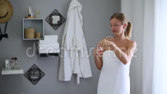 淋浴后裹着毛巾的漂亮女人在脖子上喷香水视频的预览图