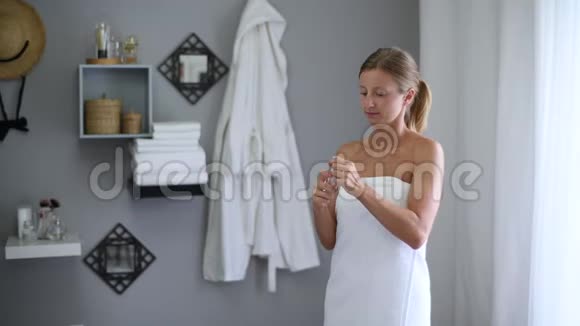 淋浴后裹着毛巾的漂亮女人在脸上喷着微层状的水视频的预览图