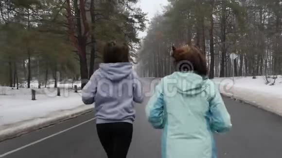 快乐的年长和年轻的高加索女人在冬天的雪地公园里奔跑交谈和微笑关闭后跟射击慢点视频的预览图