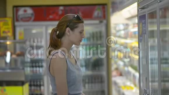 年轻漂亮的女人在超市里选择矿泉水而亚洲旅行视频的预览图