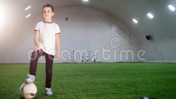 室内足球场一个小男孩站着把腿放在球上视频的预览图