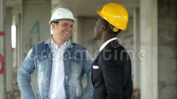 开朗的专业施工经理和非洲商人在施工现场交谈和微笑视频的预览图