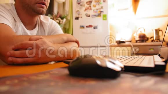 男人坐在家里的厨房桌子上男人用电脑看显示器屏幕近距离射击视频的预览图