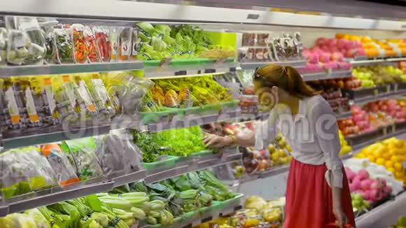 年轻的美国女人选择和闻绿色沙拉站在超市视频的预览图