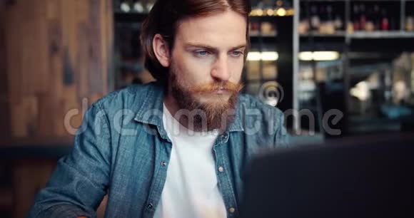 精力充沛的雄性嬉皮士在笔记本电脑上工作视频的预览图