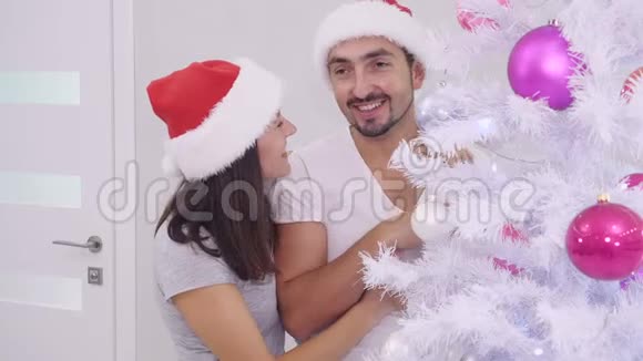 冬季寒冷的新年夜晚装饰圣诞树的性感情侣室内视频视频的预览图