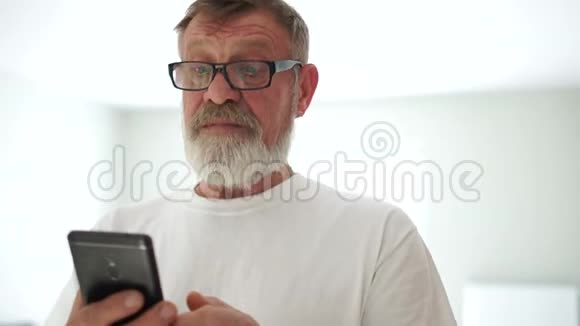 一位手里拿着手机的英俊男子的特写肖像祖父收到了他孙子的留言视频的预览图