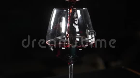 葡萄酒在黑色背景下缓慢地倒入酒杯将红酒从瓶颈倒入酒杯视频的预览图