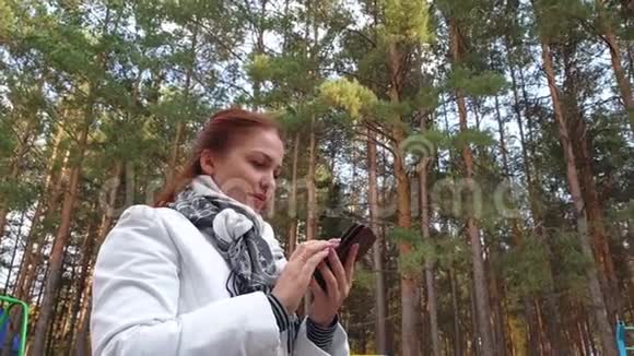 秋季公园有手机通讯和现代数字技术的生活方式妇女视频的预览图