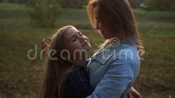 女学生拥抱她美丽的母亲在秋天公园散步母亲节视频的预览图