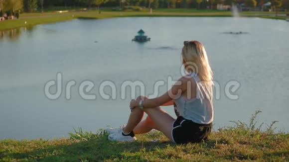 苗条的女孩坐在山上看着美丽的欧洲风格城市美丽的图画景观和美丽的湖泊视频的预览图