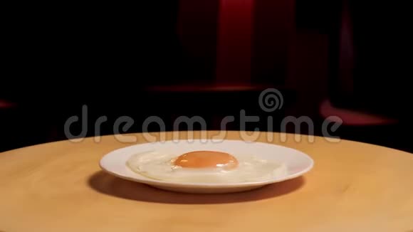 煎蛋放在盘子上在黑暗的房间背景上的木板上旋转库存录像关上白色玻璃板视频的预览图