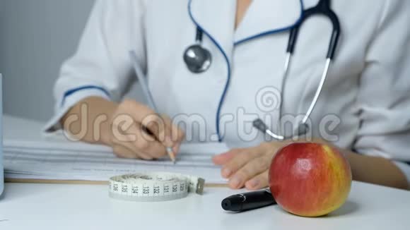 女医生营养学家在一张桌子上填写饮食计划关闭视频的预览图