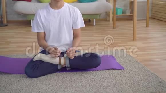 年轻的亚洲男人坐在垫子上练习瑜伽视频的预览图