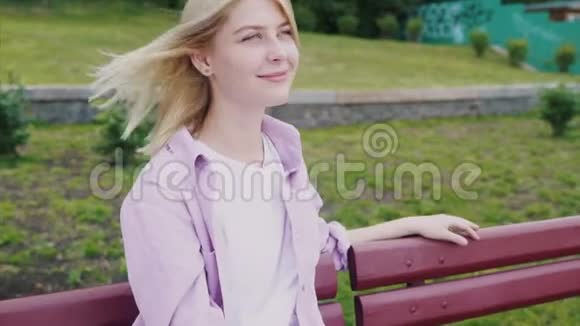 在公园木制长凳上休息的迷人时髦女孩的肖像视频的预览图