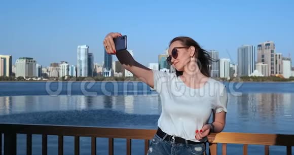 户外肖像年轻迷人的女性在时尚的服装制作自拍手机摄像头POV视频的预览图