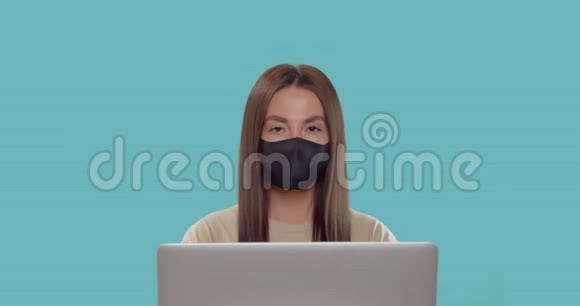 戴口罩的深褐色头发的女性在蓝色的bg上显示了OK标志视频的预览图