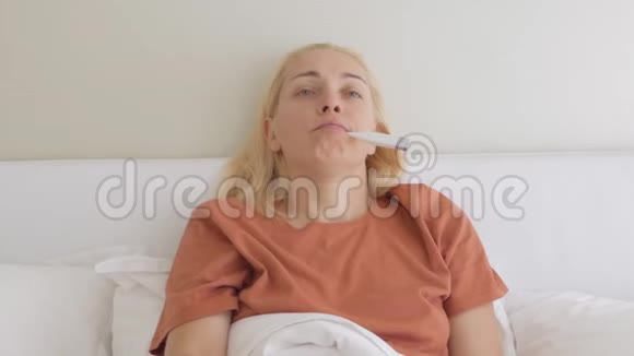 一名患流感的患病妇女在家里卧床用电子温度计测量体温视频的预览图