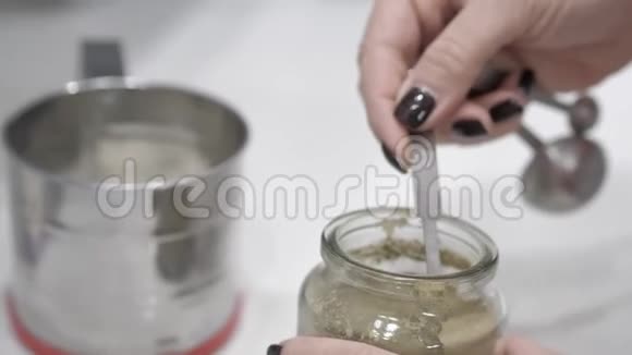 女性的手用测量勺把灰色粉末放入铁瓷容器中视频的预览图