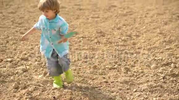 小男孩在阳光明媚的一天在花园里吃蔬菜幼儿时代花园工具农业和农业种植视频的预览图