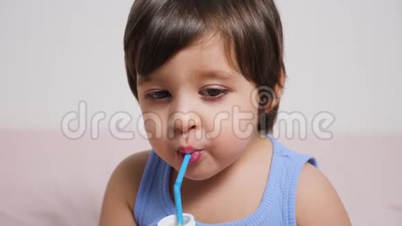 穿蓝色t恤的小男孩坐在家里的床上喝牛奶视频的预览图