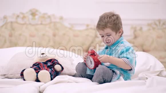 儿童在卧室设置闹钟脸平静的男孩把最喜欢的玩具放在床上该睡觉了小孩把毛绒熊放在附近视频的预览图
