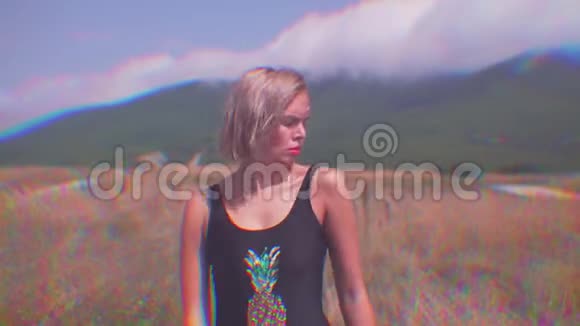 性感女孩在阳光明媚的日子里在山上的一条路上跳舞效果像镜子和RGB故障加速有趣的视频视频的预览图